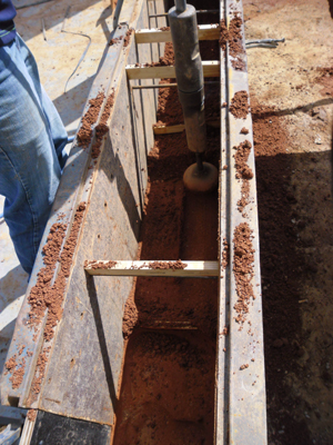 Use oil operated hand rammers to compact a layer of soil within formwork
