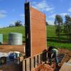 Stripping the rammed earth formwork after lifts have been completed and soil mix has began to cure
